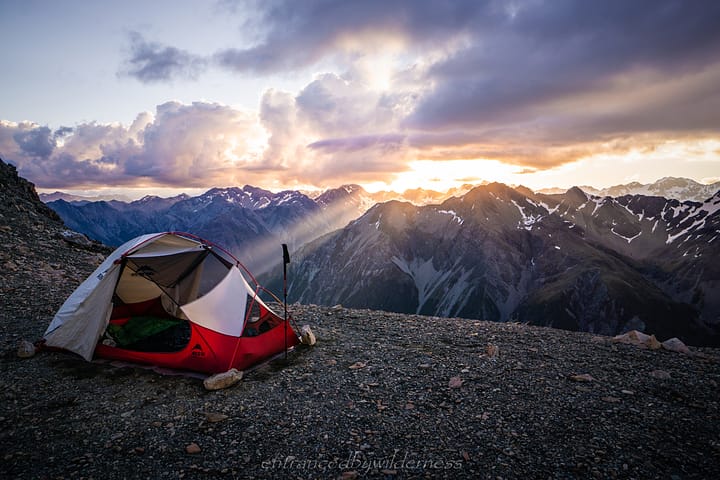 tent camping with a mountain range and sunset